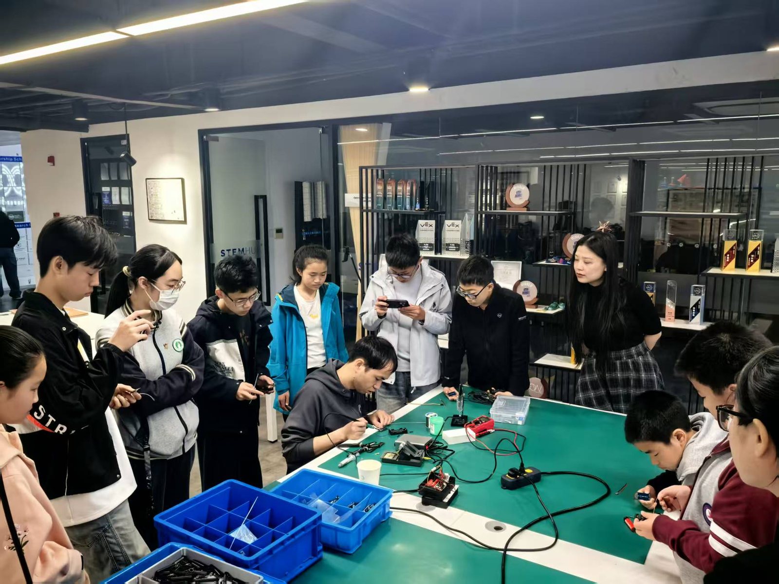 青少年围在工作台旁共同进行电子制作